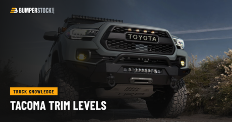Gray 2016-2023 Toyota Tacoma with a TOYOTA-letter grille and an aftermarket steel front bumper on a rocky trail