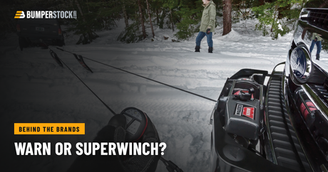 A Warn 16.5ti-s winch on the front of a Ford, its rope run out to a Jeep in the snow, a gloved hand holding the remote