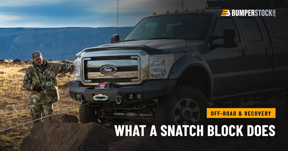 Ford Super Duty with a Warn winch bumper, winch rope run out, a man holding the remote